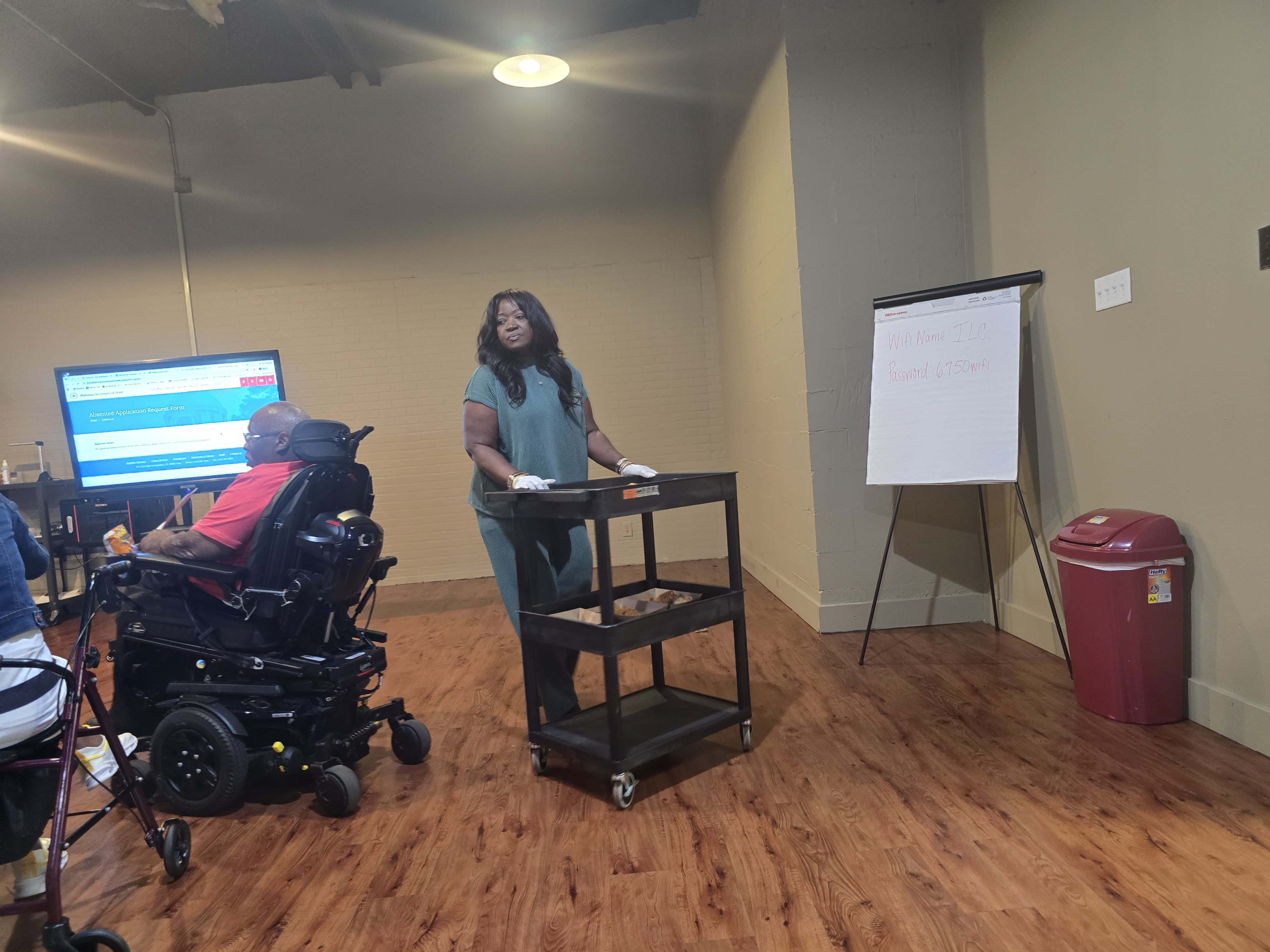 Cyneria Austin handing out chicken lunches during the September 2026 Spinal Cord Injury Support Group meeting while members listen to guest speaker Bernadette Allen.